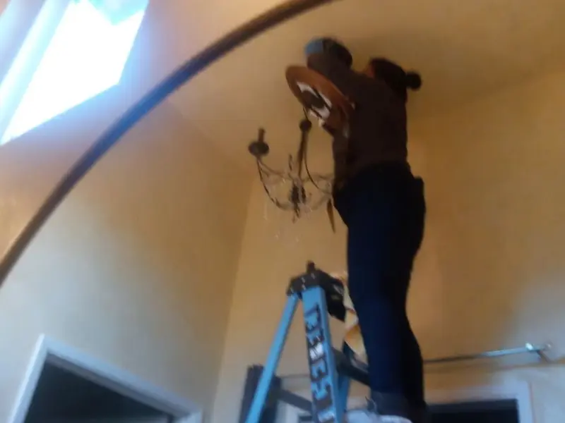 Electrician installing a chandelier in a Callaway residence